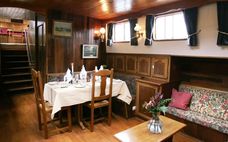 Saloon and dining interior aboard luxury hotel barge.