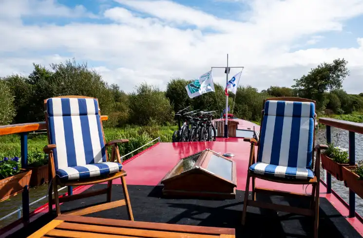 The hotel barge sundeck with two chairs and bicycles river cruising in Brittany.