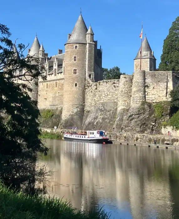 small luxury hotel barge moored next to French chateau in Brittany