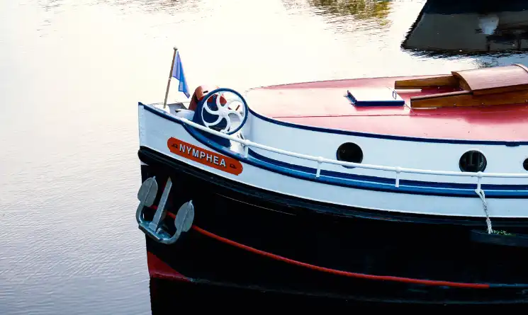 The bow of a classic hotel barge in a peaceful setting.