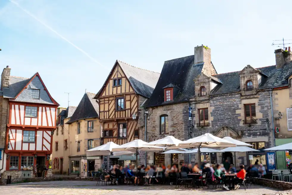 A historic town center in Brittany showing half-timbered houses and people dining outside.